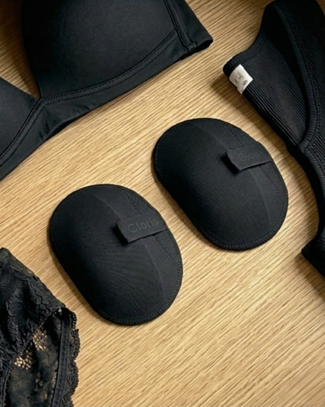 Black Gloris removable shoulder shapers beside black bras and lingerie